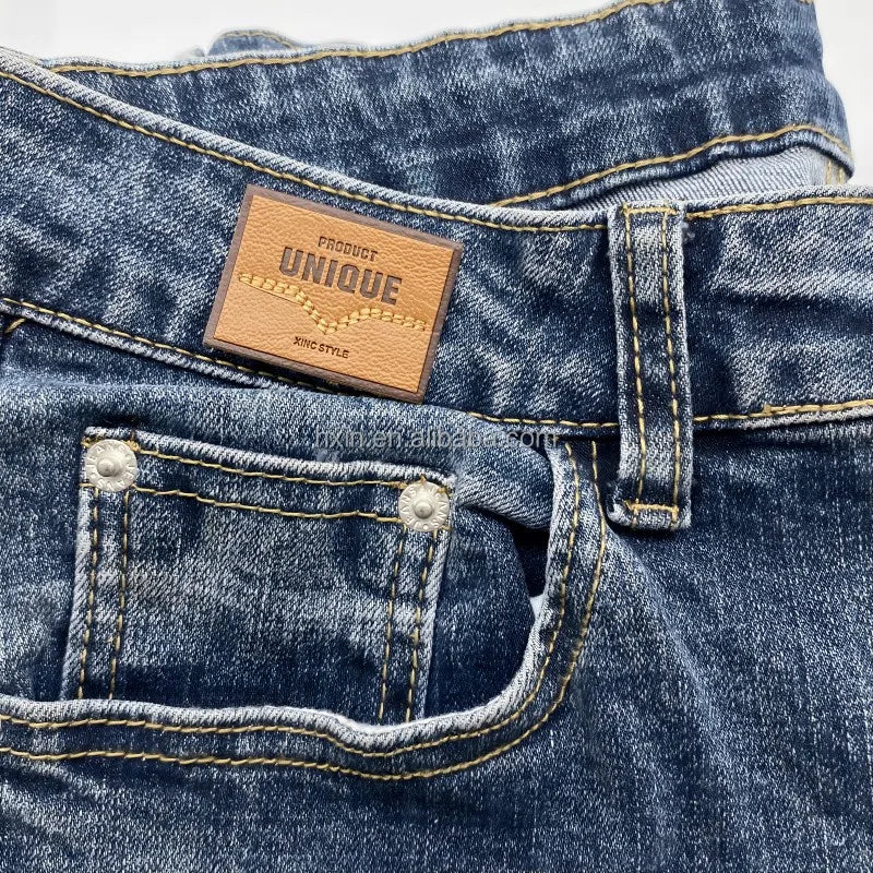 Юқори сифатли махсус ювилиши мумкин бўлган нақшинкор логотип жинси кўйлаги учун ПУ тери ёрлиғи ёрлиғига тикилган